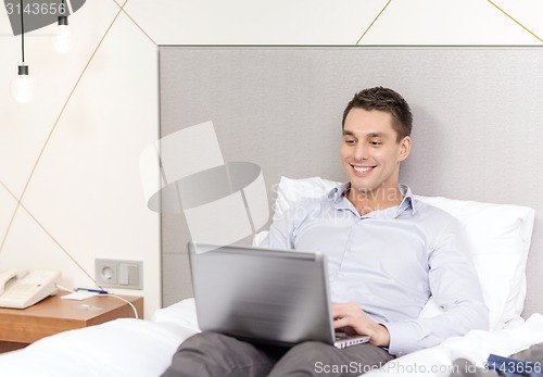 Image of happy businesswoman with laptop in hotel room