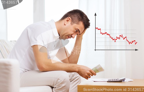 Image of man with money and calculator at home