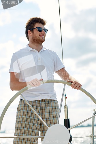 Image of young man in sunglasses steering wheel on yacht