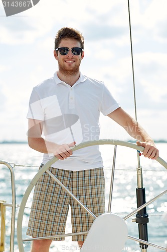 Image of young man in sunglasses steering wheel on yacht