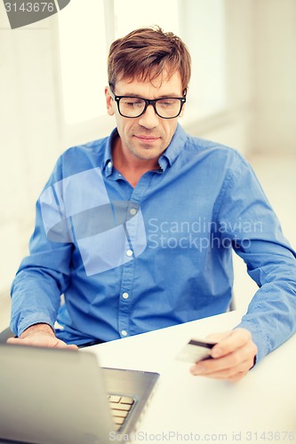 Image of man with laptop and credit card at home