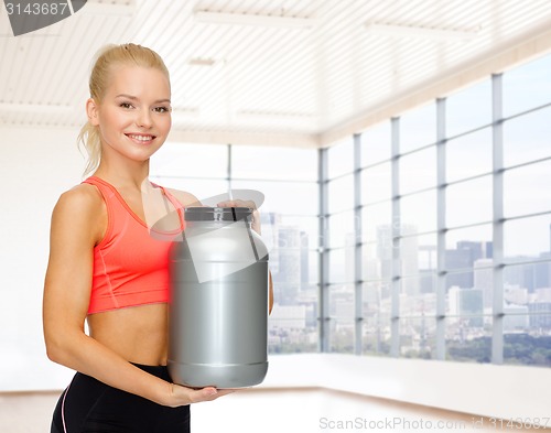 Image of smiling spory woman holding protein jar