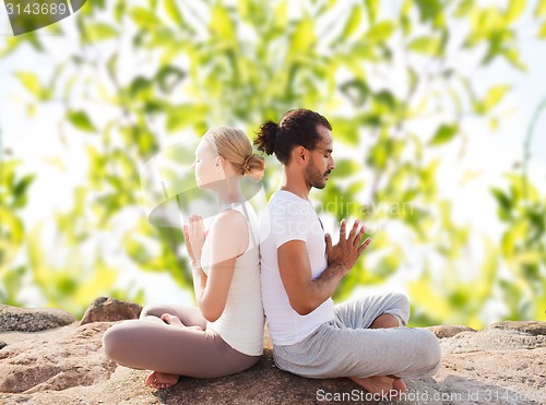 Image of smiling couple making yoga exercises outdoors
