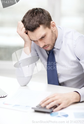 Image of stressed businessman with laptop and documents