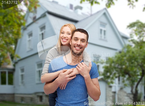 Image of smiling couple hugging over house background