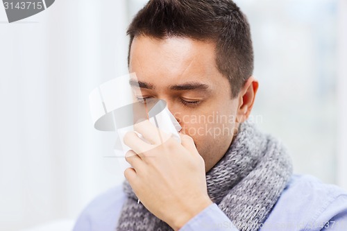 Image of close up of ill man with flu blowing nose at home