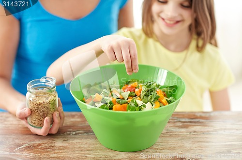 Image of close up of happy family cooking salad in kitchen