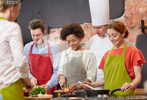 Image of happy friends and chef cook cooking in kitchen