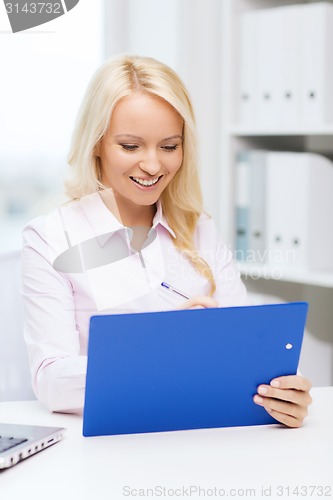 Image of smiling businesswoman with clipboard in office