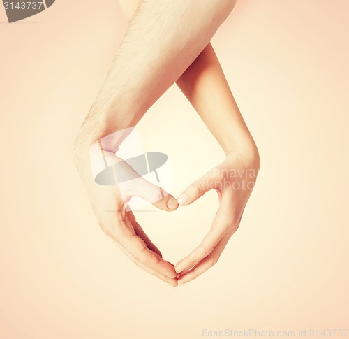 Image of woman and man hands showing heart shape