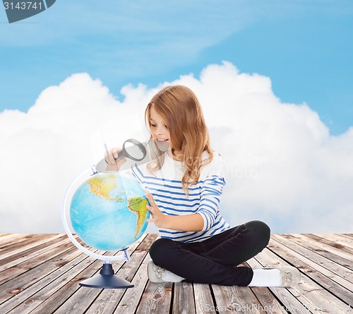 Image of happy girl looking at globe with magnifier