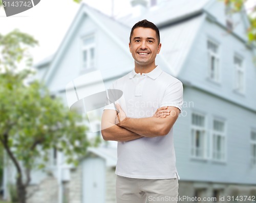 Image of smiling man in white t-shirt over house background