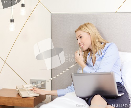 Image of businesswoman with laptop and phone in hotel room