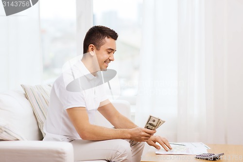 Image of man with papers and calculator at home