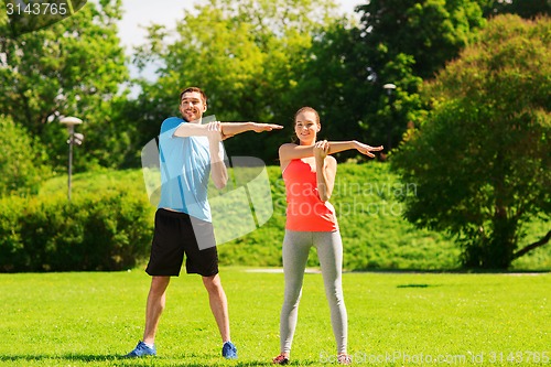 Image of smiling couple stretching outdoors
