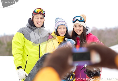 Image of happy friends with snowboards and smartphone