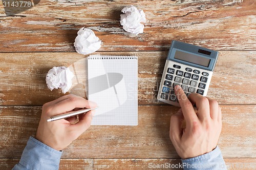 Image of close up of hands with calculator and notebook