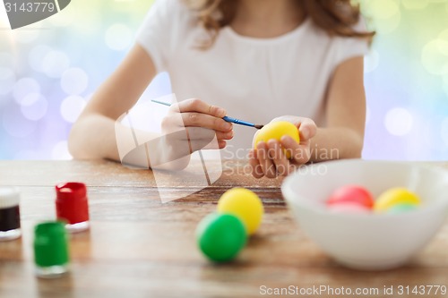 Image of close up of girl with brush coloring easter eggs