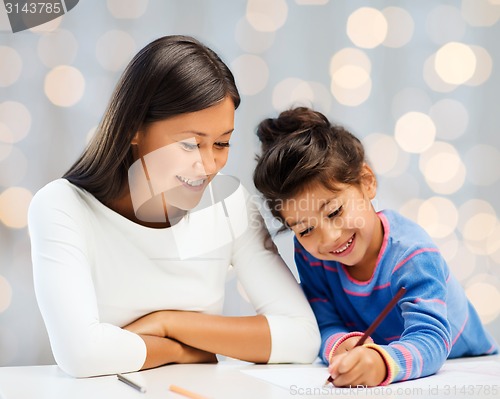 Image of happy mother and daughter drawing with pencils