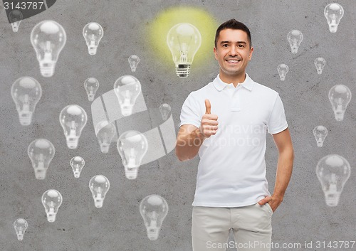 Image of smiling man showing thumbs up over lighting bulbs