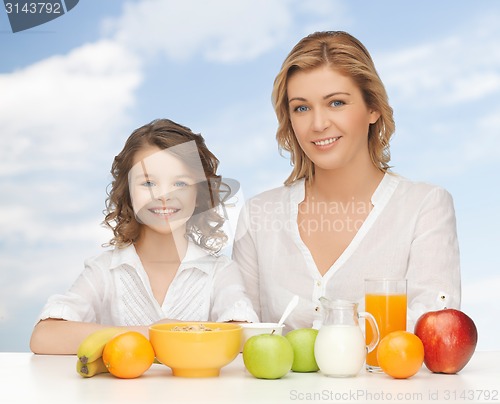 Image of happy mother and daughter eating breakfast