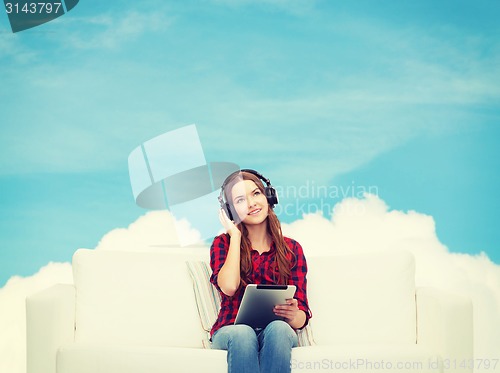 Image of girl sitting on sofa with headphones and tablet pc