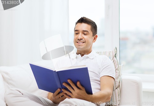 Image of happy man reading book at home