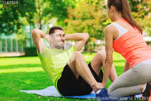 Image of smiling man doing exercises on mat outdoors