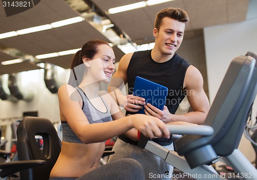 Image of happy woman with trainer on exercise bike in gym