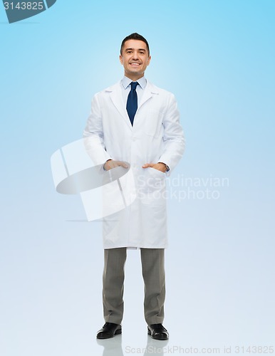 Image of smiling male doctor in white coat over blue