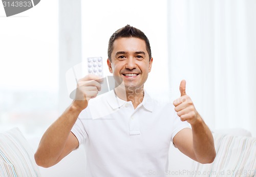 Image of happy man with pack of pills showing thumbs up