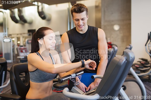 Image of happy woman with trainer on exercise bike in gym