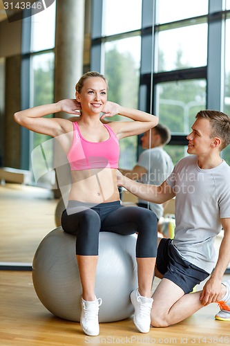 Image of smiling man and woman with exercise ball in gym