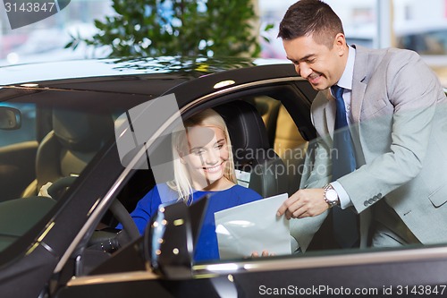 Image of happy woman with car dealer in auto show or salon