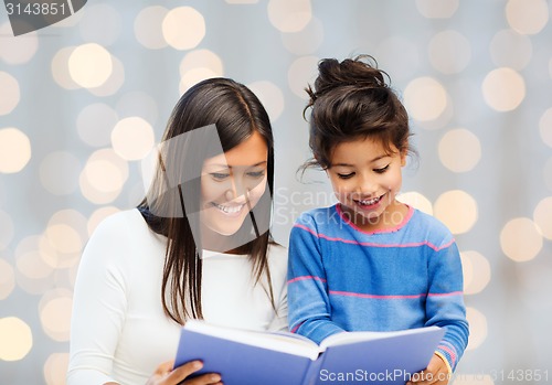 Image of happy mother and little daughter reading book