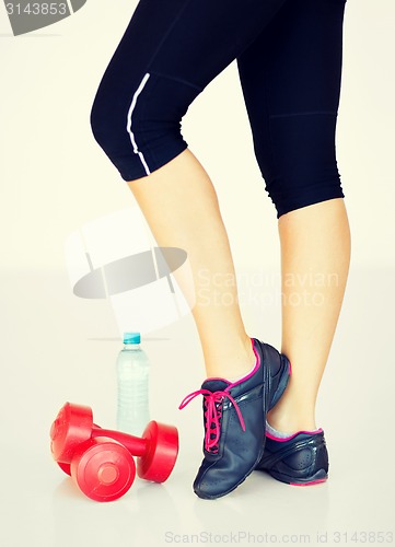 Image of sporty woman legs with light red dumbbells
