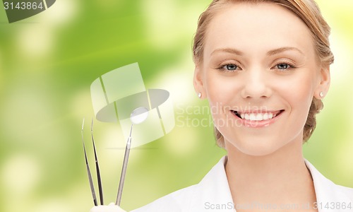 Image of happy young female dentist with tools