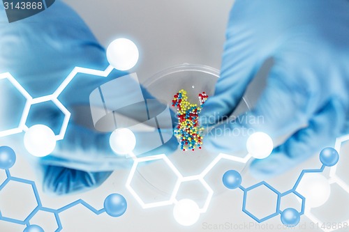 Image of close up of scientist hands holding pill in lab