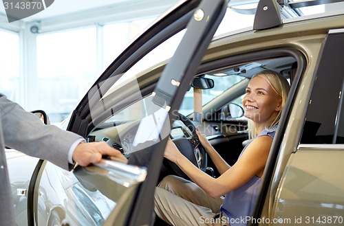 Image of happy woman with car dealer in auto show or salon