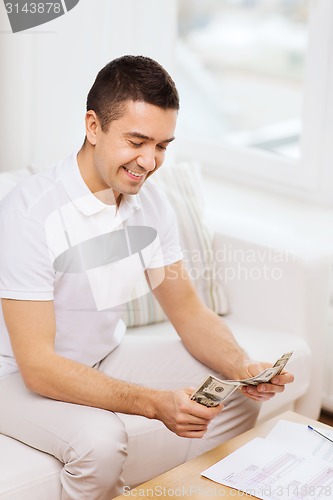 Image of man with papers and calculator at home