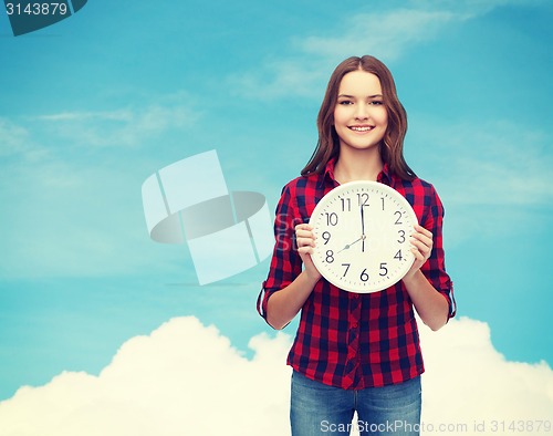 Image of young woman in casual clothes with wall clock