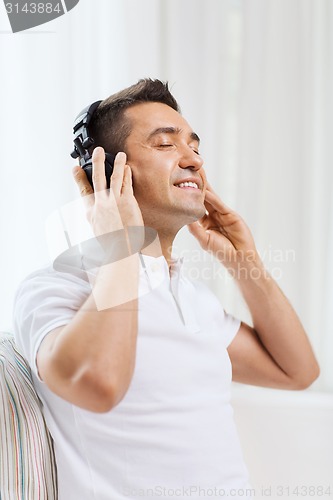 Image of happy man in headphones listening to music at home