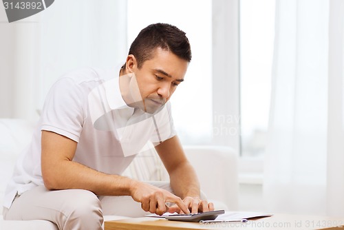 Image of man with papers and calculator at home