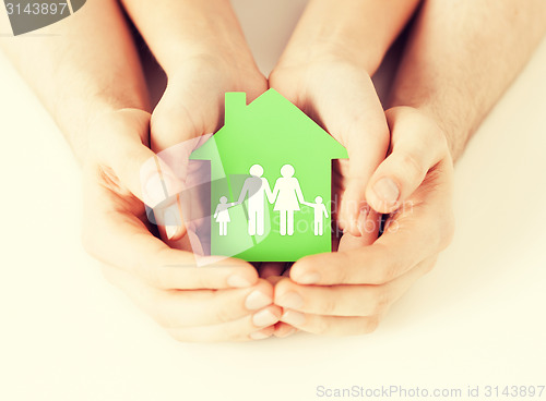 Image of hands holding green house with family