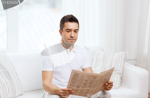 Image of man reading newspaper at home