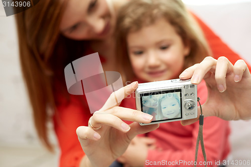 Image of close up of happy mother and daughter with camera