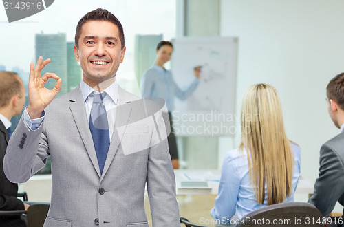 Image of happy businessman in suit showing ok hand sign
