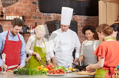 Image of happy friends and chef cook cooking in kitchen