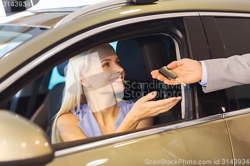 Image of happy woman getting car key in auto show or salon