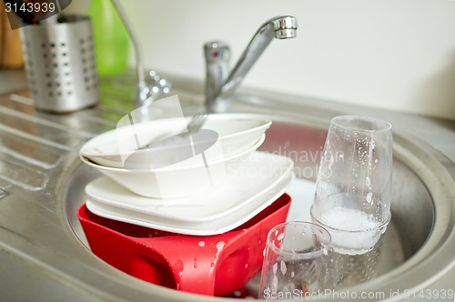 Image of close up of dirty dishes washing in kitchen sink